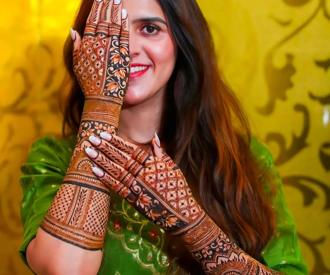 A happy bride is my best advertisement. Here you can see how the full-arm mehndi looks with the bridal outfit, creating a complete and stunning look for your wedding photos. The design features intricate jaali work and floral patterns.
