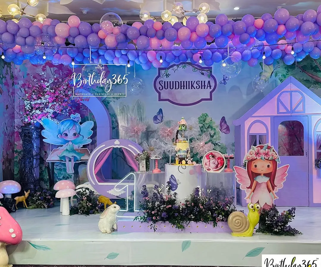 An enchanting fairy-themed birthday party brought to life in dreamy shades of purple. This immersive setup includes a custom fairy house, whimsical character cutouts, oversized mushrooms, and a ceiling adorned with a cascade of balloons and lights.