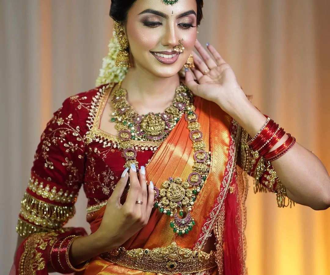 This is my signature South Indian bridal look. The rich, warm tones of this Kanjivaram-style silk saree paired with a deep red velvet blouse create an evergreen elegance that is perfect for your muhurtham.
