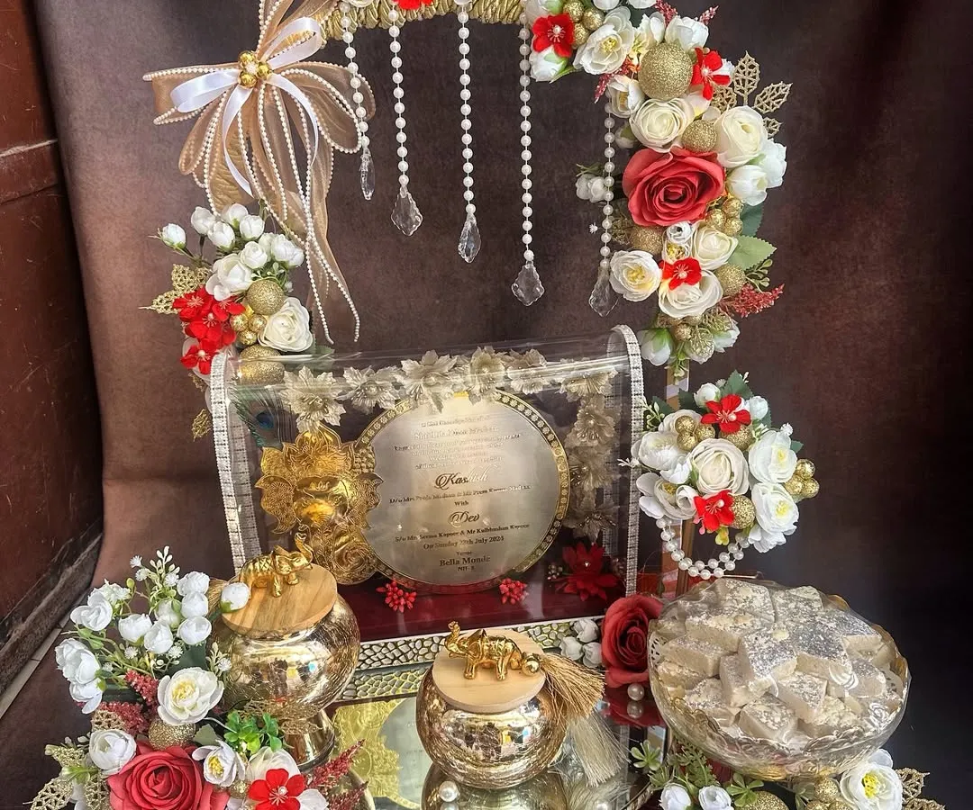 The first wedding invitation sets the tone for the entire celebration. I designed this royal 'first card' platter to be a grand statement, combining traditional elements with elegant red and gold floral arrangements to give the families a truly special moment.