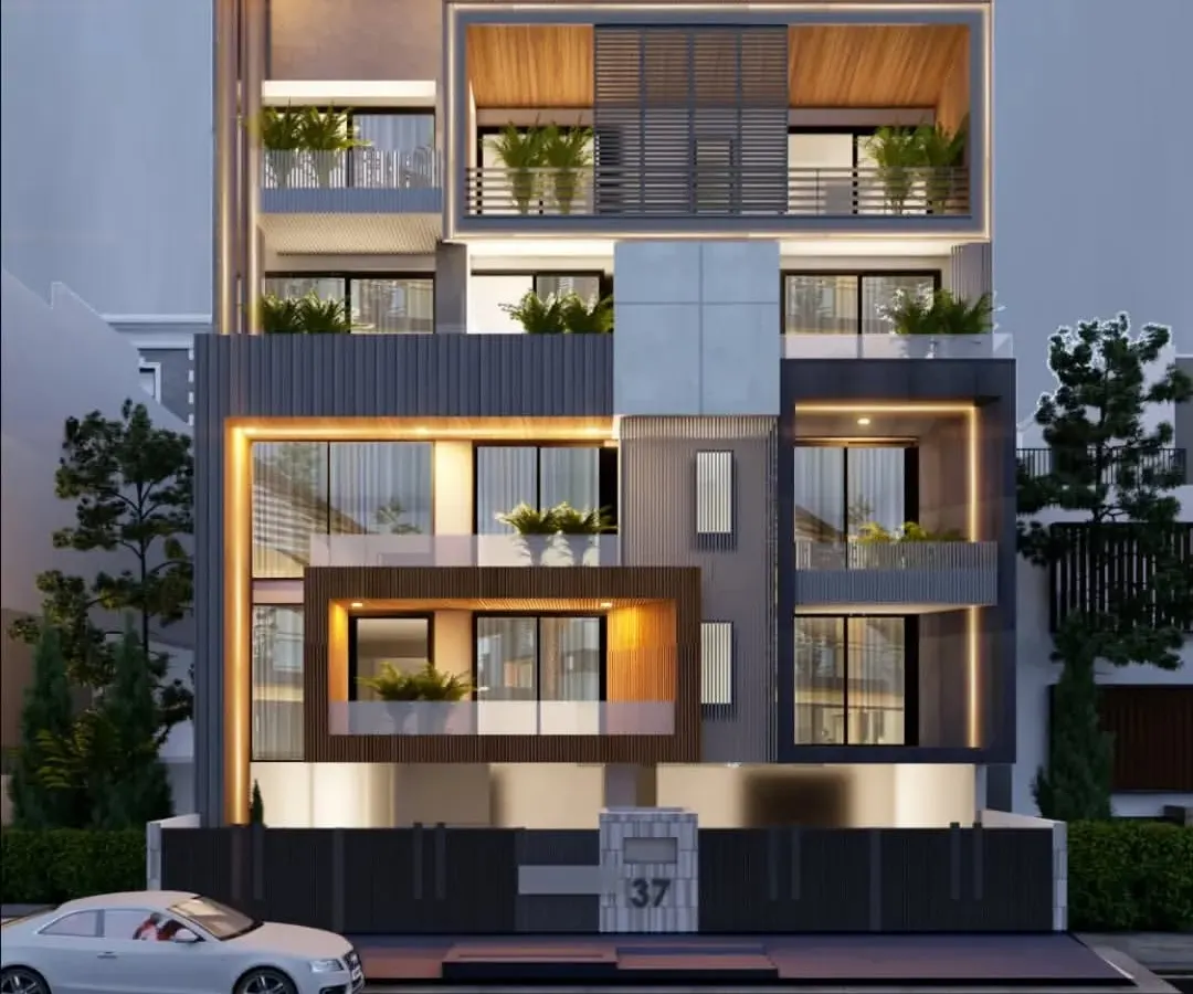 An evening view of a modern residential building, showcasing how strategic lighting design can transform a structure after dark. The interplay of illuminated voids, warm interior glows, and facade highlights creates a dramatic and sophisticated presence, emphasizing the building's multi-layered form.