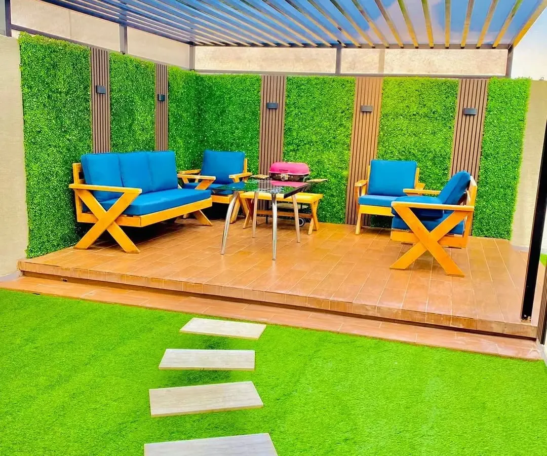 Imagine your terrace as the perfect spot for a sunny weekend brunch. We created this vibrant outdoor lounge with comfortable seating, durable artificial turf, and a signature green wall accented with wood panels, all under a modern pergola.