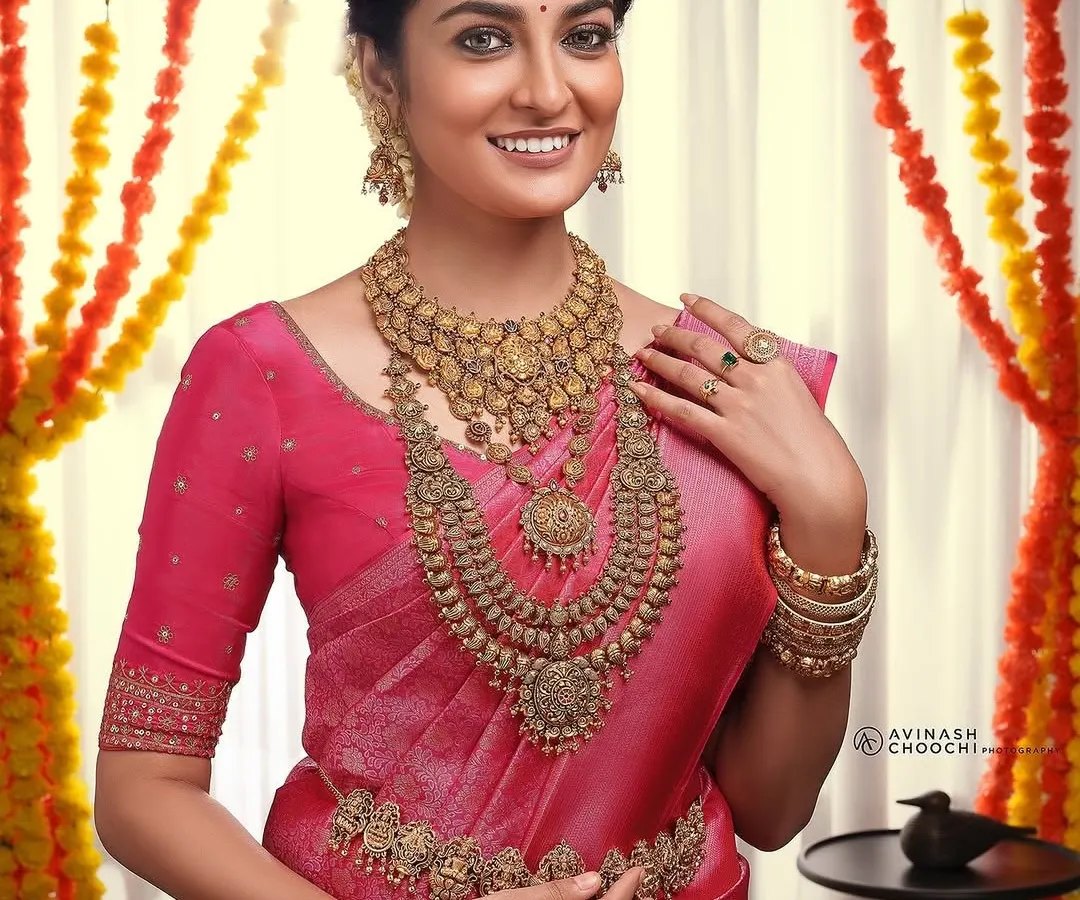A stunning traditional bridal look created for a Rajakumari Gold photoshoot. My goal was to craft a flawless, radiant base that enhanced the model's features, allowing the intricate gold temple jewelry and vibrant pink silk saree to truly shine.