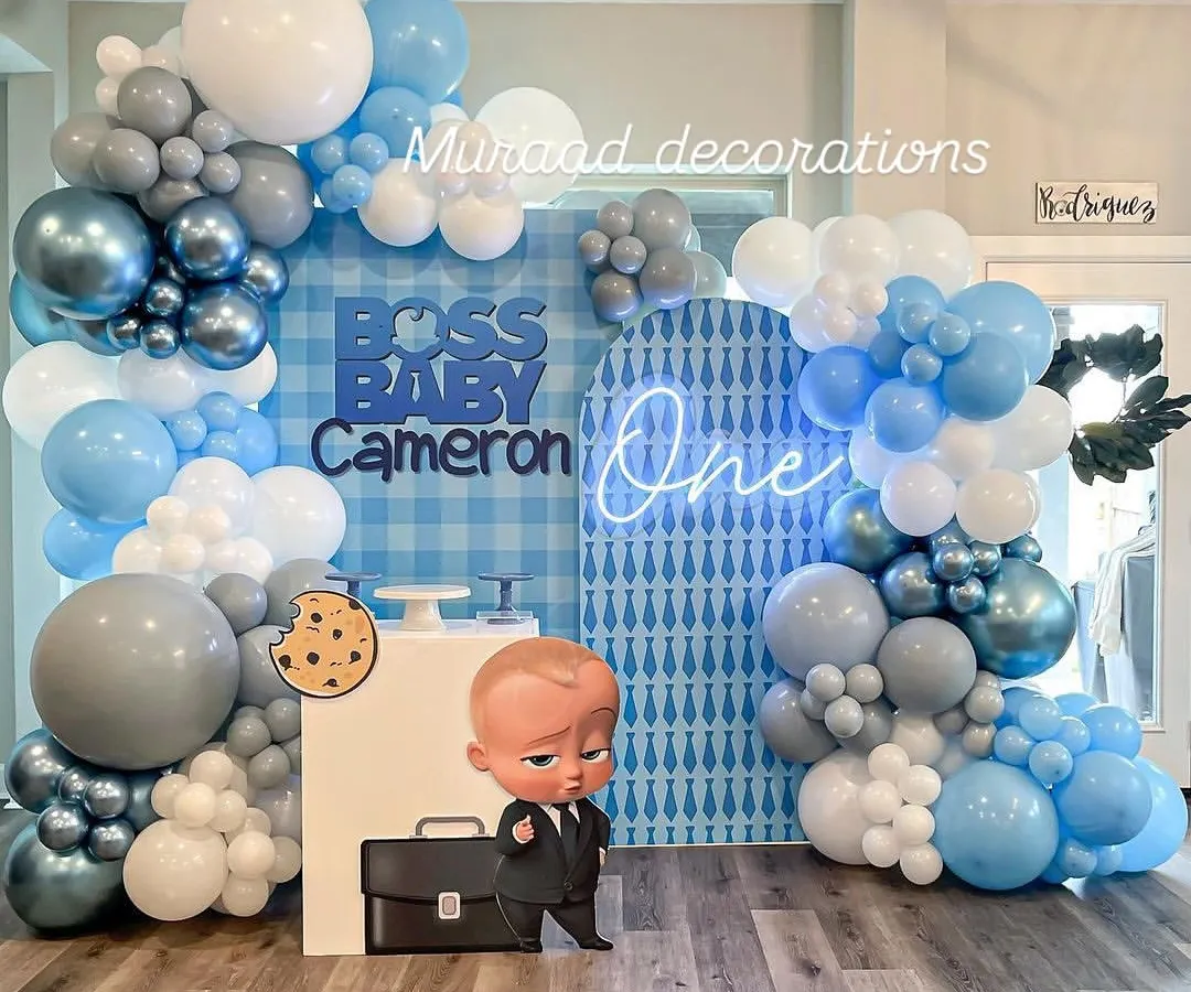 The Boss Baby theme is a huge hit for first birthdays. This setup features a custom gingham and patterned backdrop, a cool 'One' neon sign, and a life-sized character cutout, creating a playful and corporate-cute photo zone.