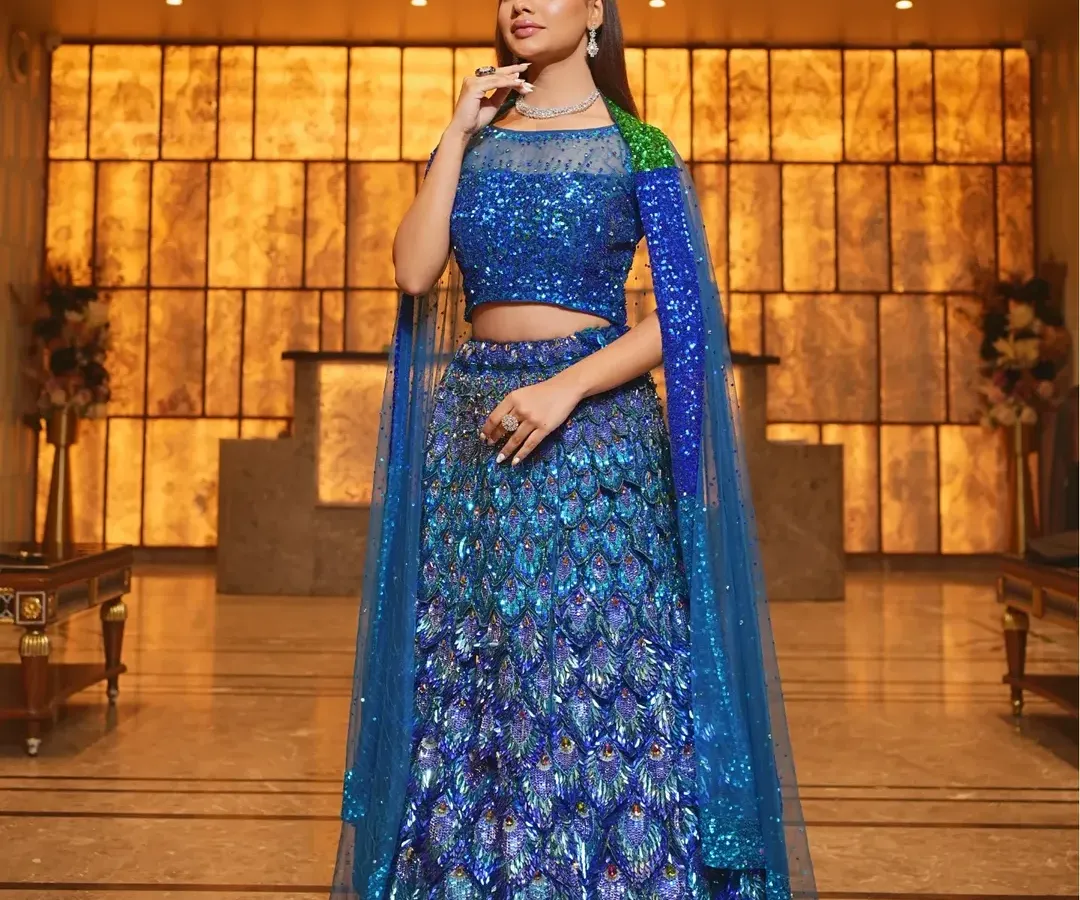Make a bold statement at your reception or cocktail party with this stunning peacock-inspired lehenga. The vibrant blue sequins and unique design are paired with a delicate diamond-style necklace to create a modern, unforgettable look.