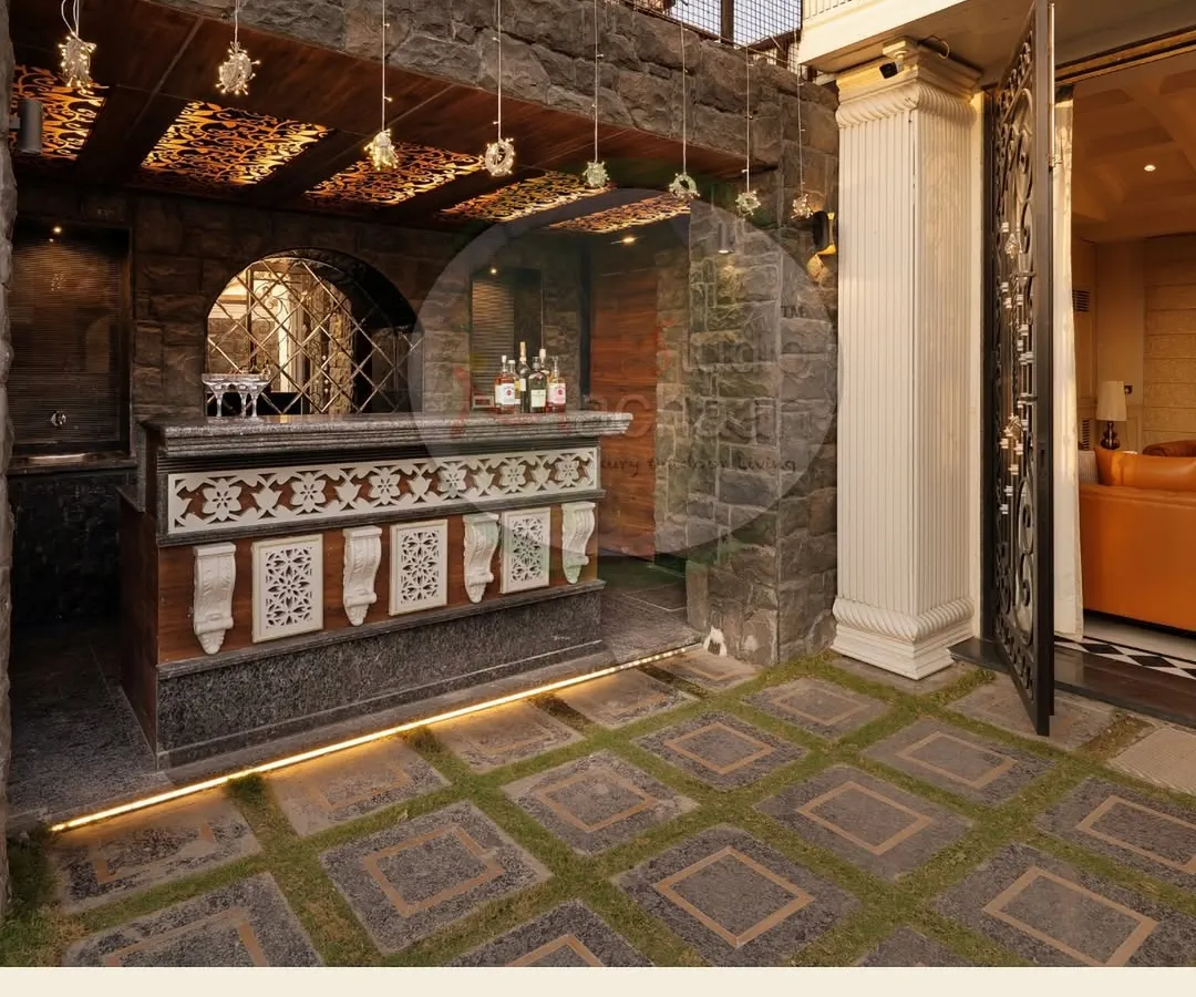 We transformed this once-empty rooftop into a sophisticated entertainment zone. The centerpiece is a custom-designed bar with intricate jaali work, set against rugged stone walls and illuminated by subtle, warm lighting. The flooring combines non-slip granite with artificial grass for a unique texture.