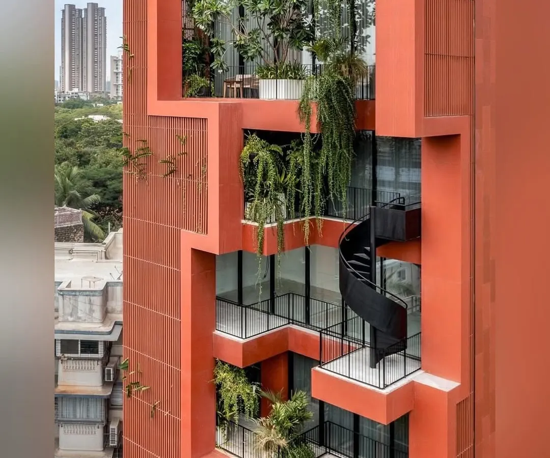 In the dense urban landscape of Mumbai, we sculpted a vertical oasis. This close-up of the Sarvasva tower shows how we integrated cascading greenery and a sculptural spiral staircase, turning the building's facade into a living, breathing garden.