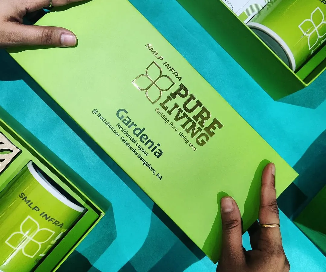 A vibrant and fully branded welcome kit for SMLP Infra. This bright green box features their logo with gold foil stamping and contains custom-printed mugs and other branded merchandise, making a bold first impression.