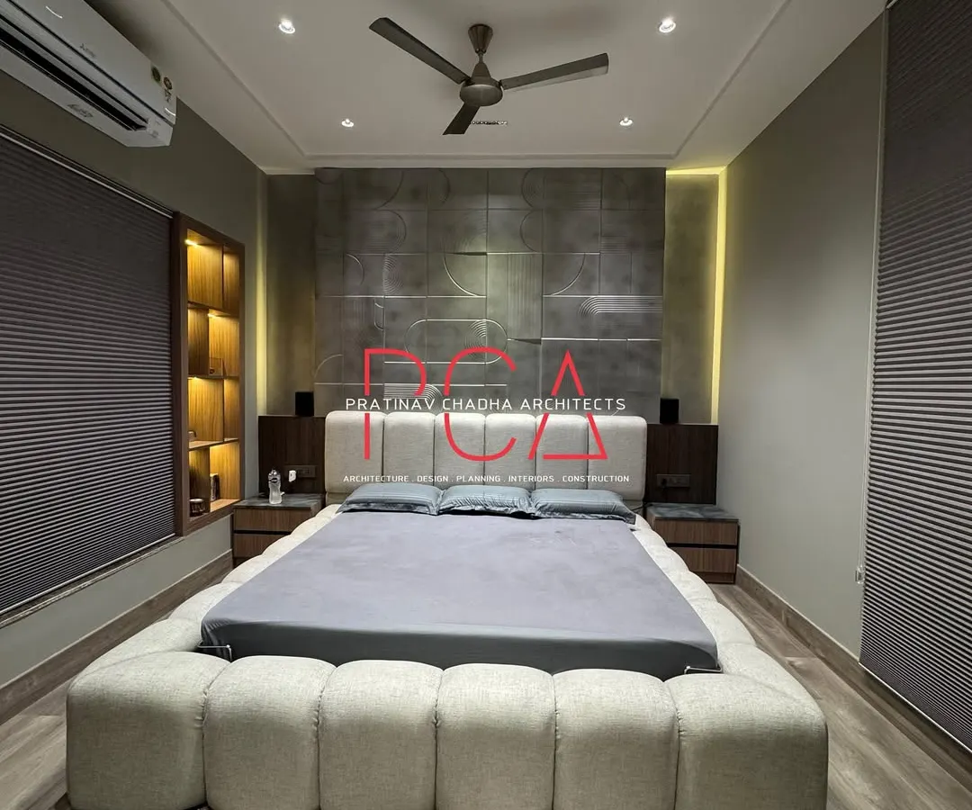 A view of a recently completed son's room, showcasing a bold and striking material palette. The design features a bed upholstered in beige bouclé fabric set against a bespoke, antique silver-finished geometric milled accent wall, creating a space that is both modern and opulent.