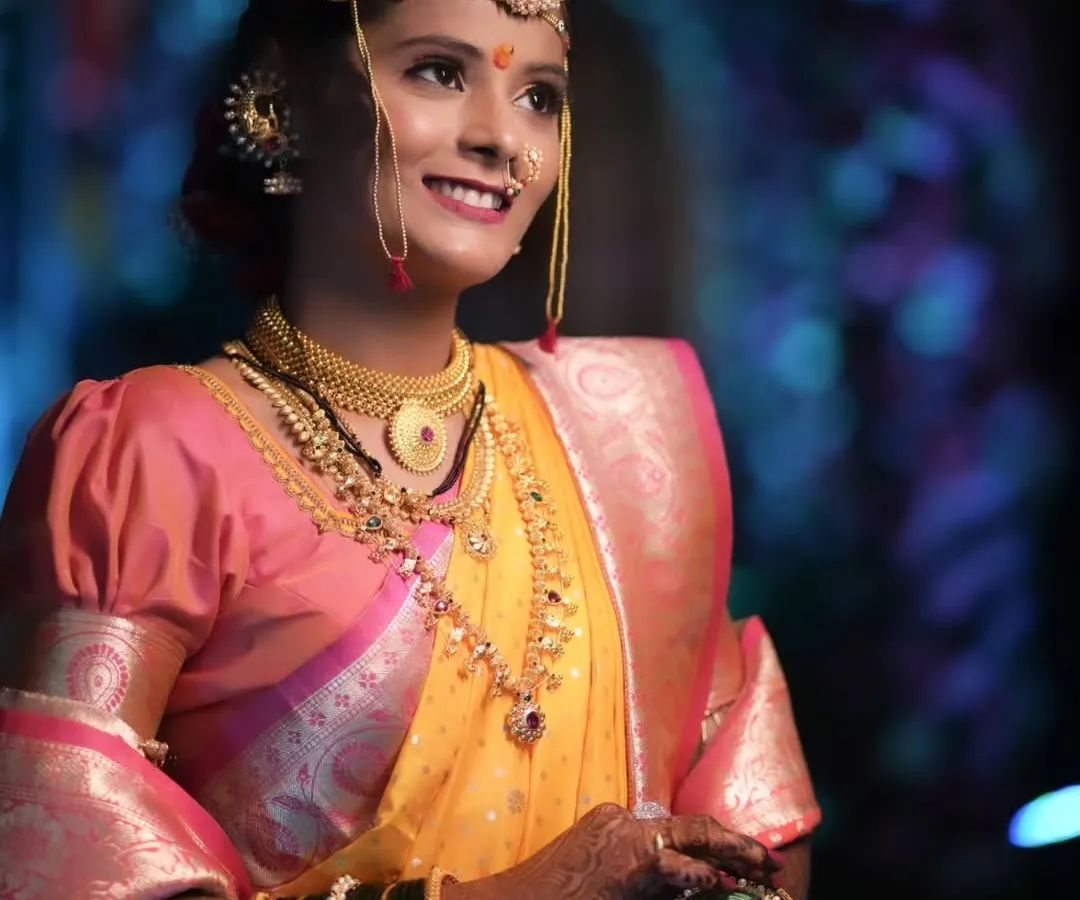 The quintessential Maharashtrian bride. This close-up highlights the traditional crescent bindi, the glow of HD makeup, and the intricate details of the nath and gold jewelry that are central to this beautiful look.