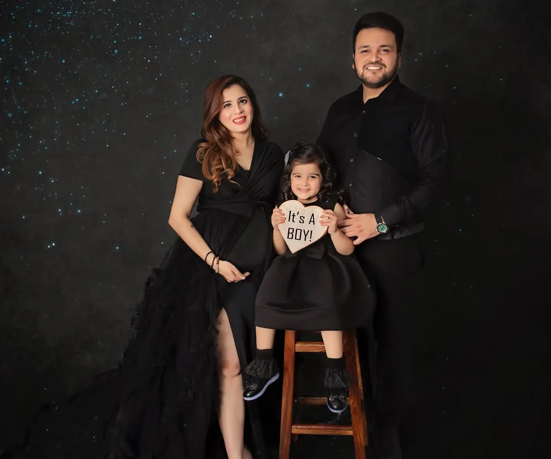 The whole family joins in to celebrate! This beautiful portrait captures the joy of a growing family, complete with a sweet "It's a Boy!" gender reveal sign against a magical starry backdrop.
