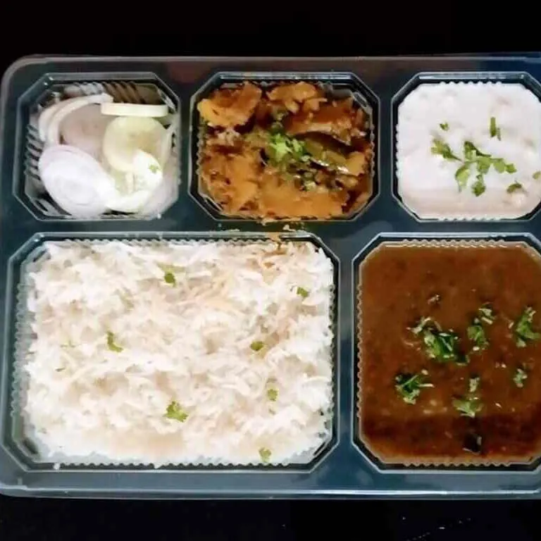 This is what our standard daily tiffin looks like. It's a complete, balanced meal with dal, sabzi, rice, and salad, all hygienically packed and ready to eat. We ensure good quantity and quality in every box.