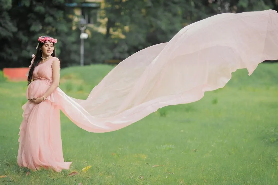 A classic portrait featuring one of my popular flying trail gowns. The soft pink fabric and the outdoor setting create a dreamy, ethereal look that celebrates your journey to motherhood.