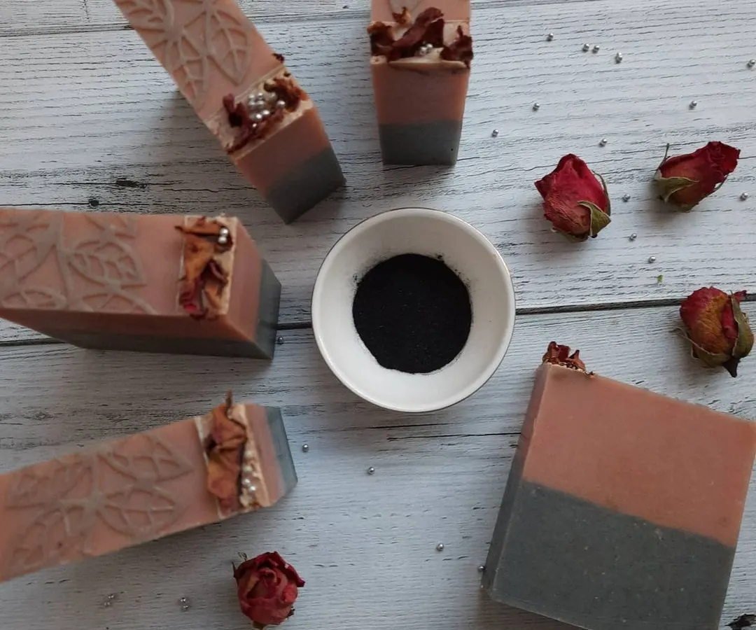 This is my Charcoal Rose soap, a customer favorite. I arrange each bar with dried rosebuds and a sprinkle of charcoal powder, showcasing the natural French pink clay and activated charcoal that work to gently detoxify your skin.