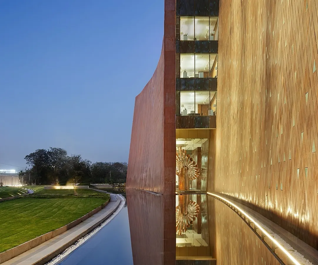 At the Zydus Headquarters in Ahmedabad, we used water as a central design element to create a serene microclimate. The building's reflection on the water's surface illustrates our philosophy of creating a seamless dialogue between the built form and the natural landscape, resulting in spaces that are both monumental and tranquil.