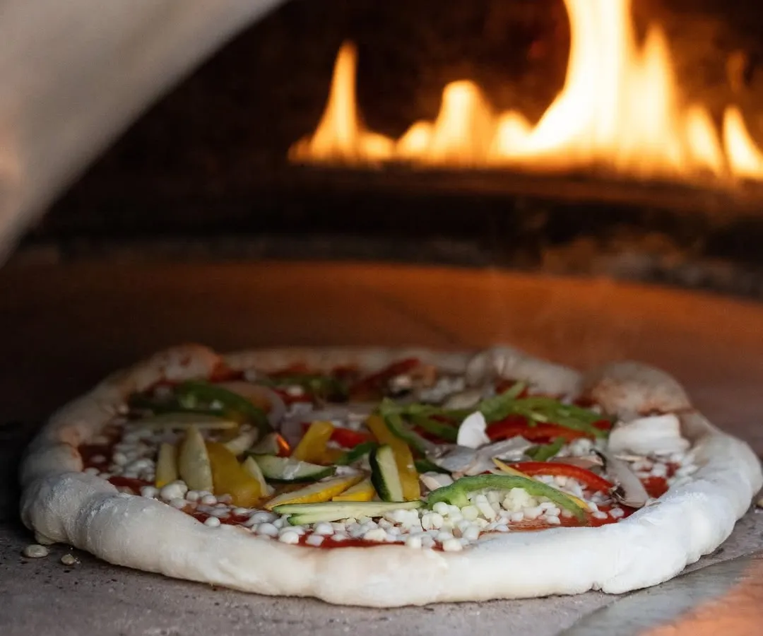The heart of Italian cooking is simplicity and quality. Here, a fresh vegetarian pizza with a sourdough base and vibrant toppings is prepared in our authentic wood-fired oven, delivering a rustic and gourmet taste of Italy to your celebration.