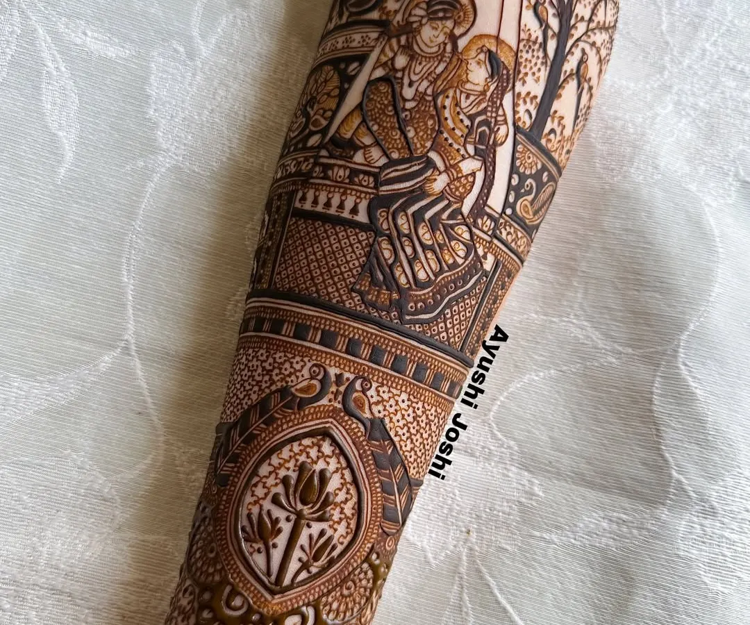 For me, mehendi is devotion. This full-sleeve design features a detailed portrait of Radha and Krishna on a swing, surrounded by divine motifs like peacocks, lotuses, and cows, creating a piece of wearable spiritual art.