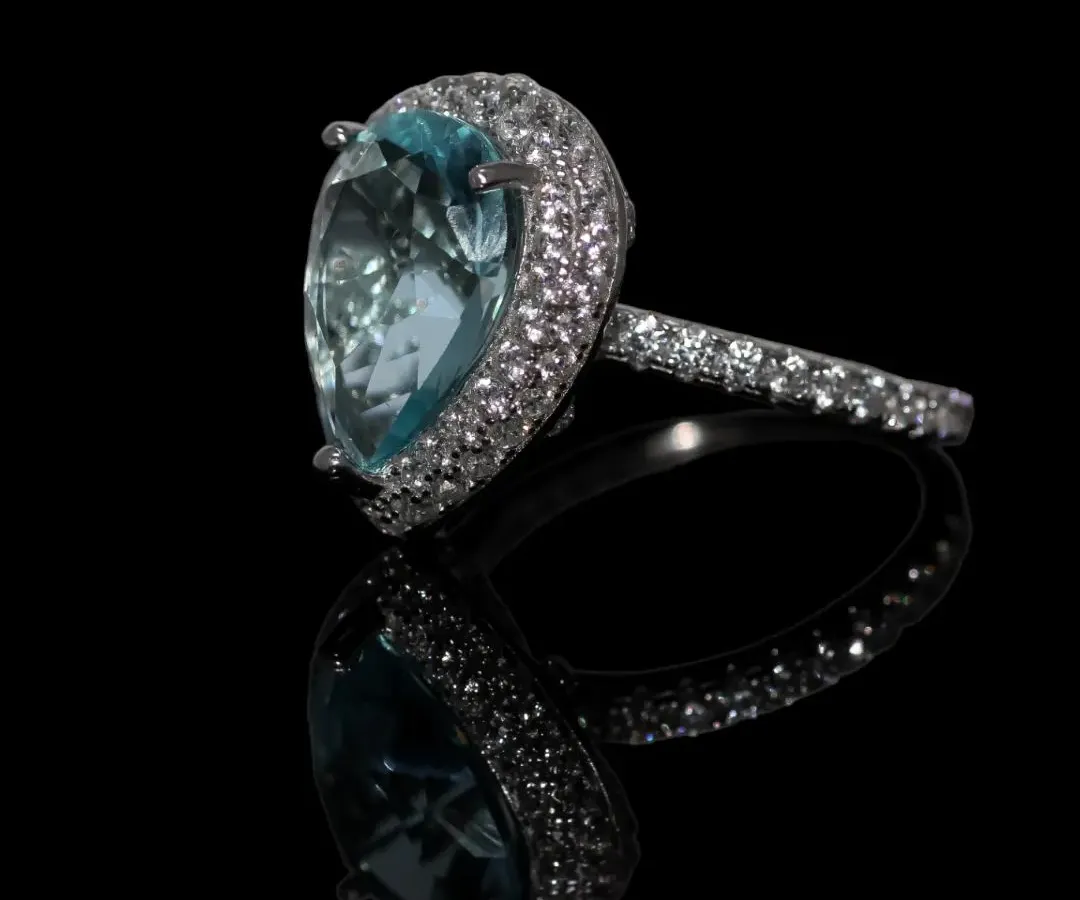 A true showstopper, this statement cocktail ring features a large, teardrop-shaped aquamarine-colored stone surrounded by a halo of sparkling zirconia. Crafted in pure 92.5 silver, it's designed for those special events where you want your jewelry to make an impact.