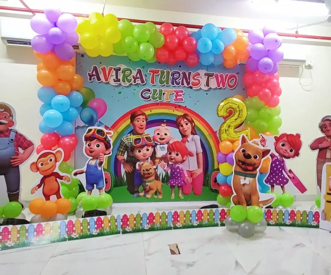 A full Cocomelon themed decoration for a second birthday party, perfect for toddlers. This setup includes a large, colorful backdrop with the entire Cocomelon family and friends, framed by a vibrant balloon garland. Life-sized character cutouts of JJ, TomTom, YoYo, and their animal friends bring the theme to life, making it an immersive experience for the little ones.
