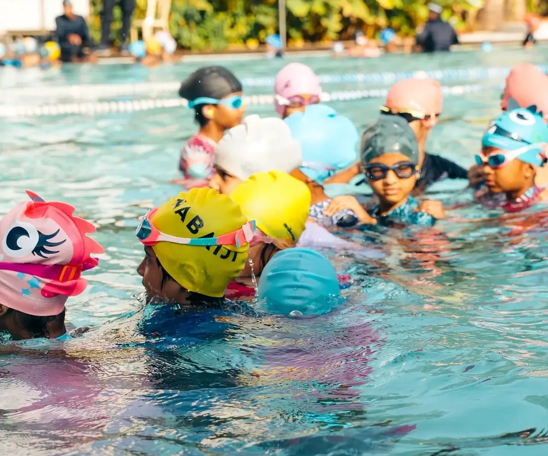 We believe swimming is about more than just technique; it's about building confidence and making friends. Here, a group of our young swimmers listens intently during a lesson, showcasing the fun, social, and engaging atmosphere we cultivate in our kids' batches.