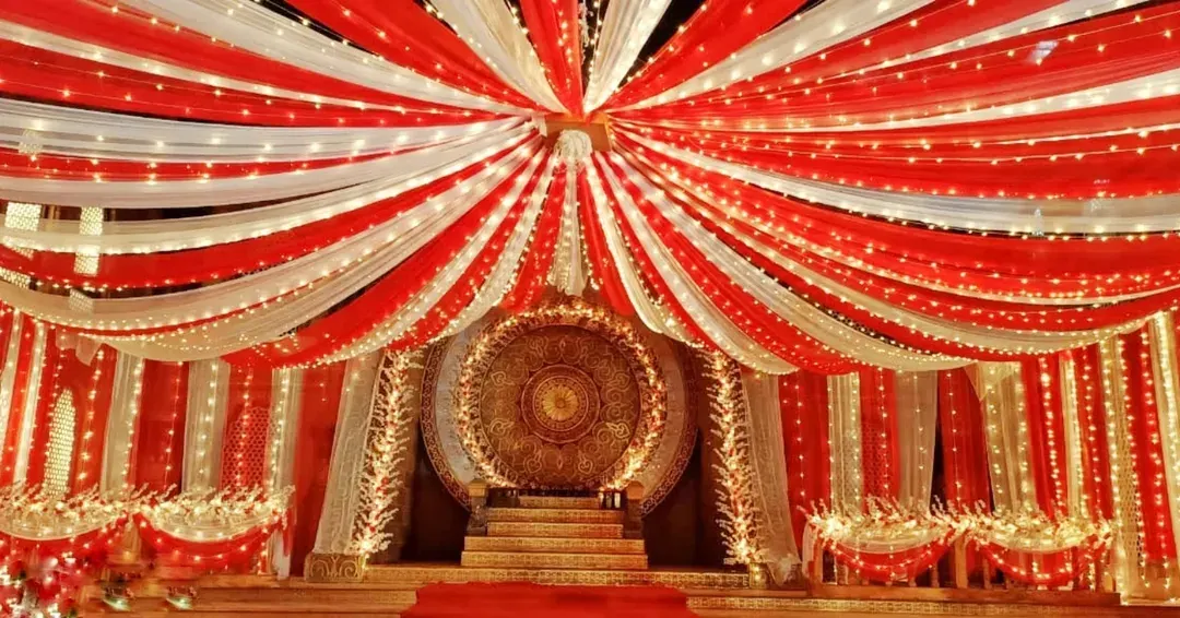 Here is a traditional stage I designed, perfect for a wedding reception or cultural festival. The design features extensive red and white fabric draping across the ceiling, intricate lighting, and a detailed golden centerpiece to create a rich, celebratory atmosphere.