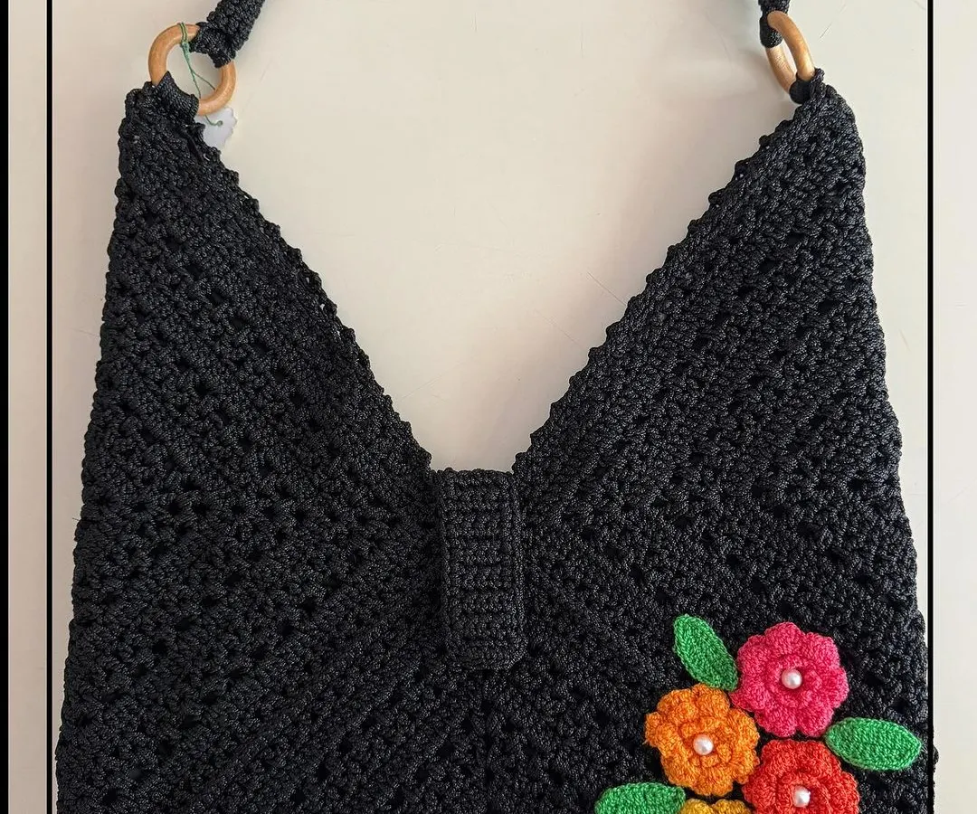 My black beauty bag is a true showstopper. The intricate crochet work is highlighted with bright, handmade flowers, creating a unique piece that will grab everyone’s attention.