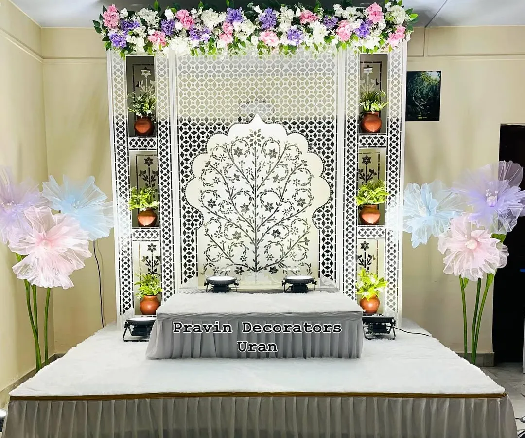 Here is an elegant, white-themed Ganpati decoration for a client's home. The centerpiece is a custom Tree of Life Jaali backdrop, complemented by a raised platform for the idol and built-in niches to display small plants and diyas.