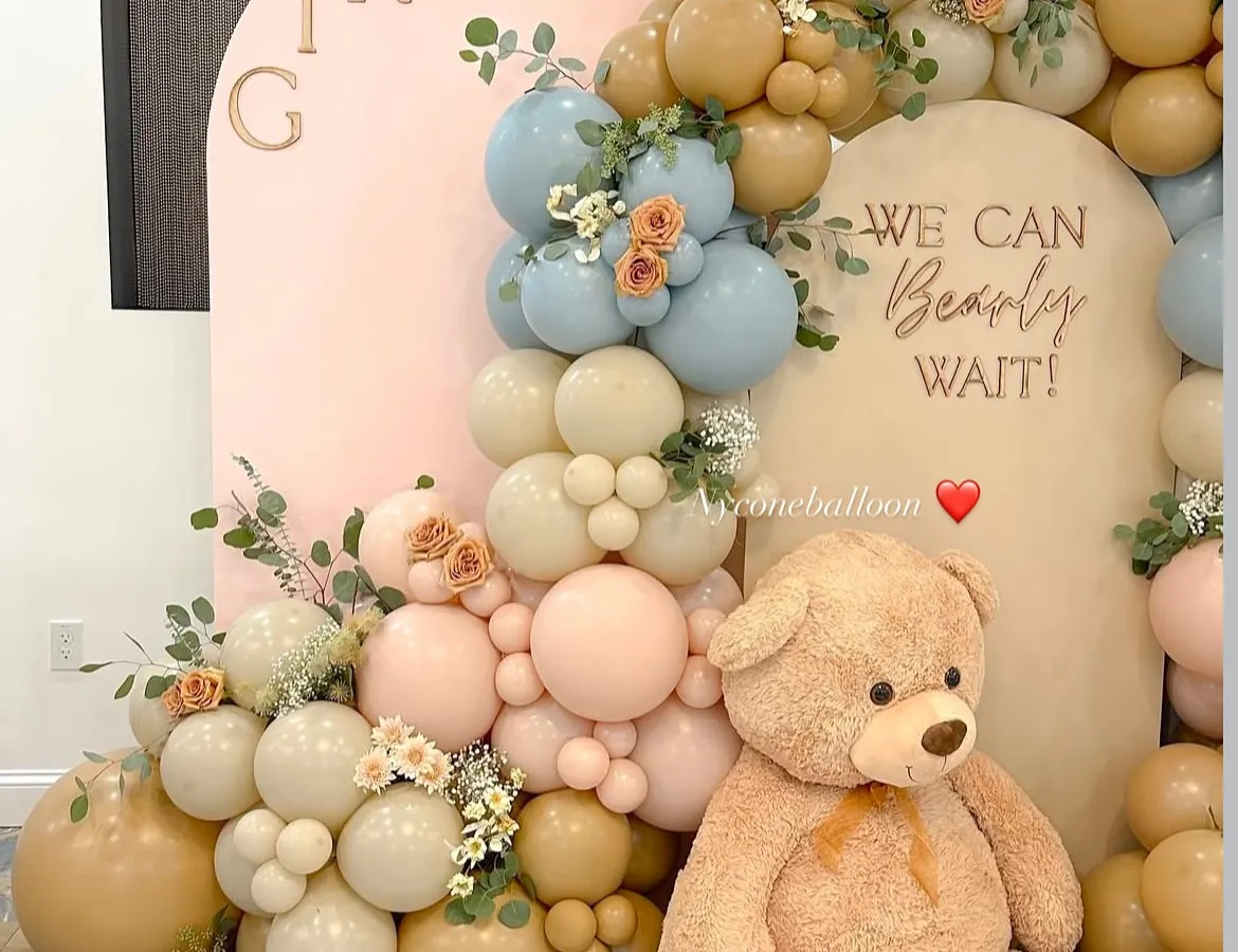 The teddy bear theme is a classic for a reason. Here is a gender reveal setup with the message 'We Can Bearly Wait', using a soft, modern palette of muted blue, pink, and beige balloons.