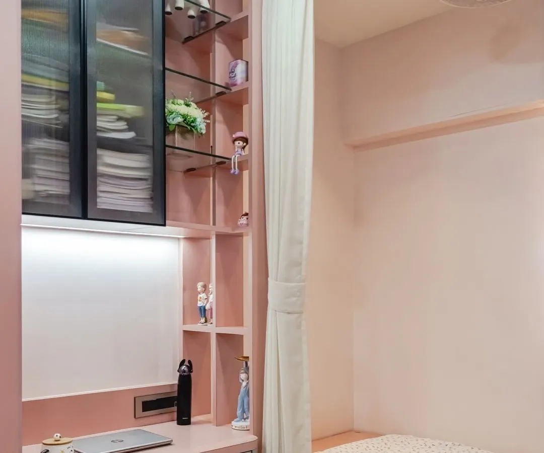For this room, I designed a compact and stylish study nook that flows seamlessly into the bedroom's storage. The soft pink tones, combined with glass-front upper cabinets and open shelving, create a space that is perfect for both focused schoolwork and displaying personal treasures.