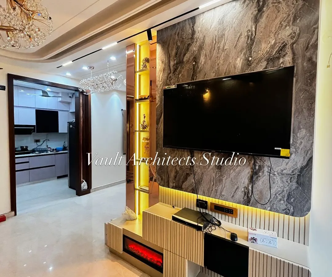 This living room showcases our approach to creating a functional and stylish entertainment zone. The design integrates a marble-finish TV panel with warm, backlit shelving and fluted details for a sophisticated look.