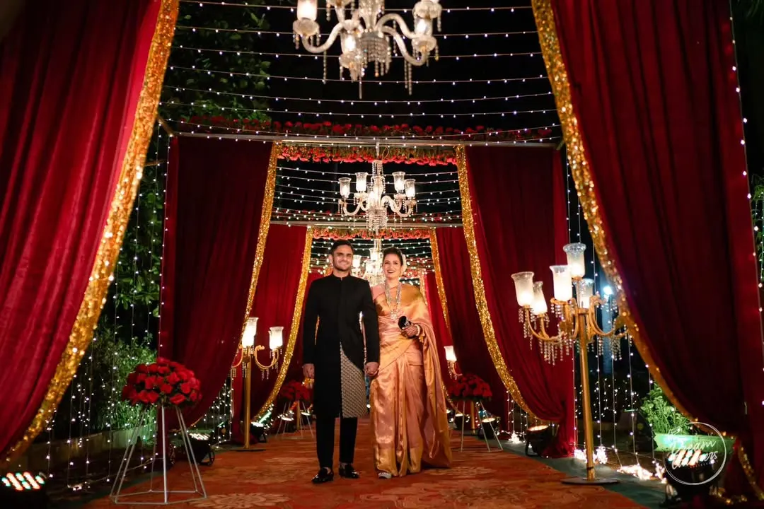 We created a grand, regal entrance for this reception, using rich red drapery, gold accents, and elegant chandeliers. This setup, illuminated by fairy lights and classic candelabras, was designed to make the couple's entrance feel like a royal affair.