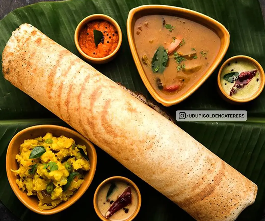 Our signature Masala Dosa, served authentically on a banana leaf. This complete platter features a perfectly crisp dosa filled with spiced potato masala, accompanied by fresh coconut chutney, tangy tomato chutney, and our flavorful vegetable sambar. It's a centerpiece for any breakfast event.
