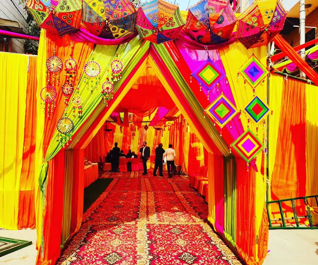 No space is too challenging. Here, I've converted an outdoor area into a grand, festive venue with a colourful tent entrance, perfect for a Haldi or Mehendi ceremony. The setup includes traditional Rajasthani umbrellas and intricate drapery.