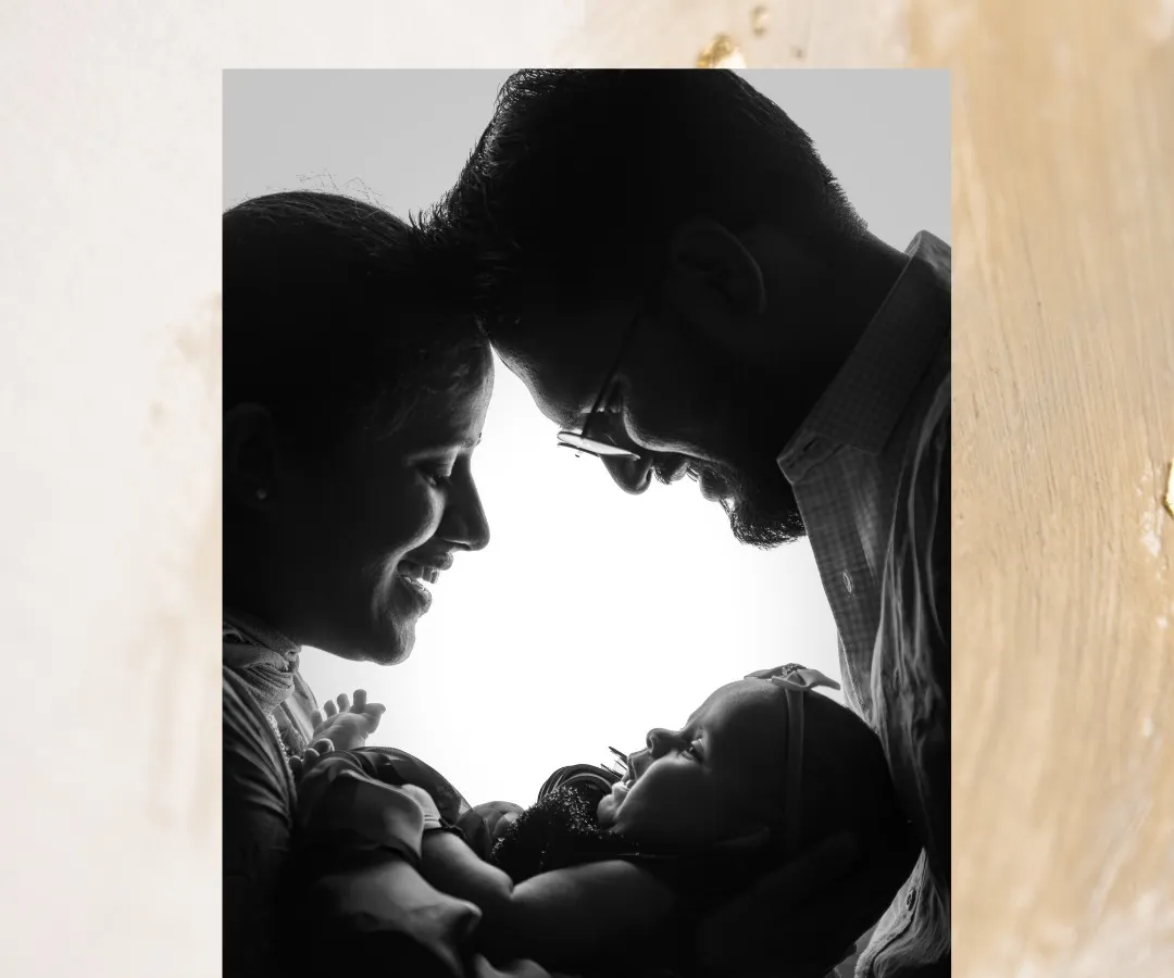 This is the art of connection. A beautiful black and white silhouette captures the pure love between new parents as they gaze down at their baby, their faces forming a circle of love around their new world.