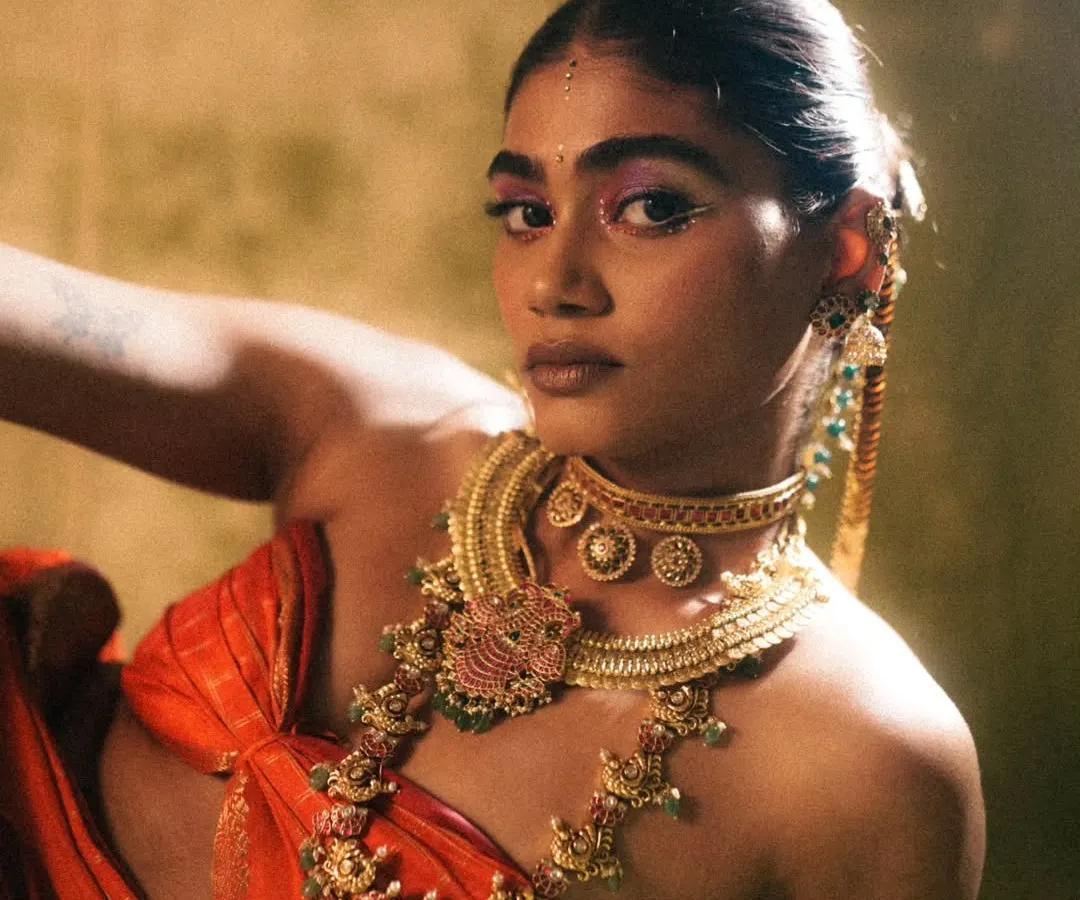 For the 'Swaṟṇavalli' series, the goal was to create a look that felt both divine and powerful. I used a vibrant magenta eyeshadow to contrast with the traditional gold jewelry and kept the skin radiant and fresh. The sleek, adorned hairstyle completes this modern interpretation of a classic aesthetic.
