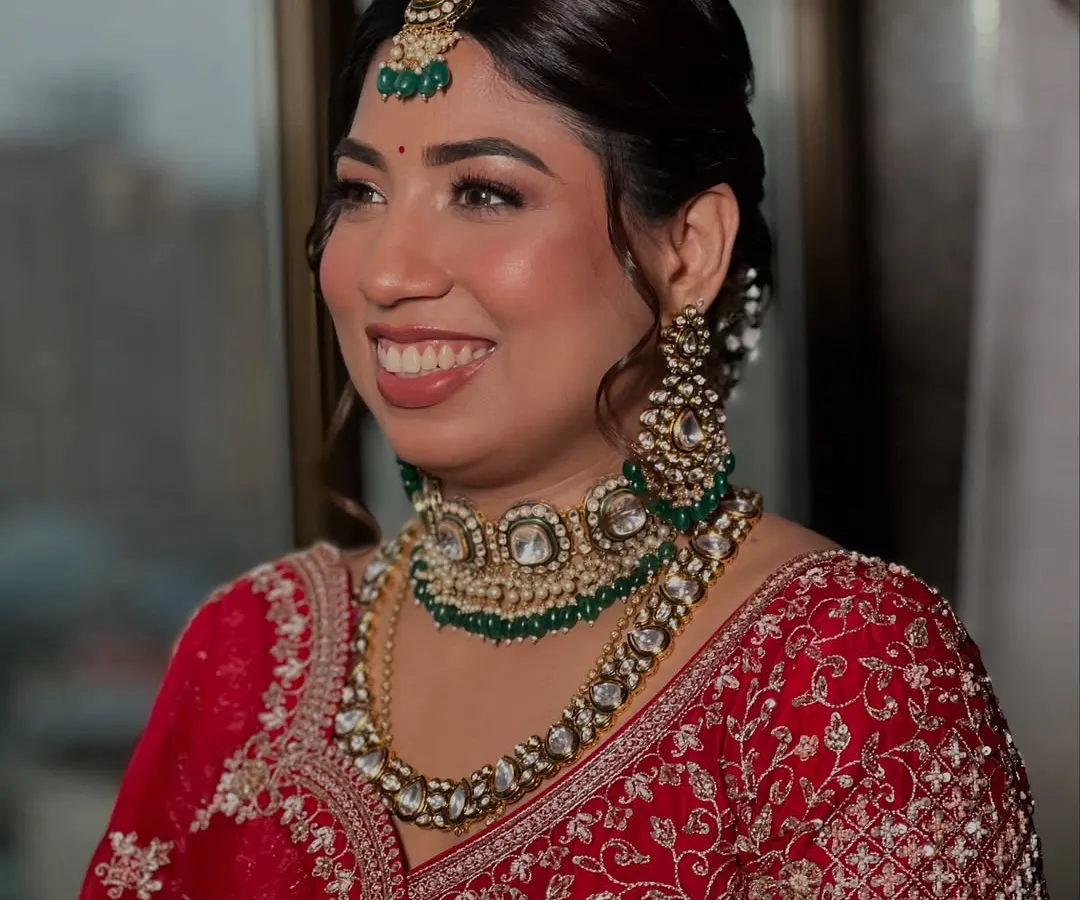 A classic Indian bride in red, looking absolutely timeless. I focused on creating that signature glass skin finish to make her complexion luminous, paired with a warm, earthy lipstick and defined eyes to make her smile the center of attention.