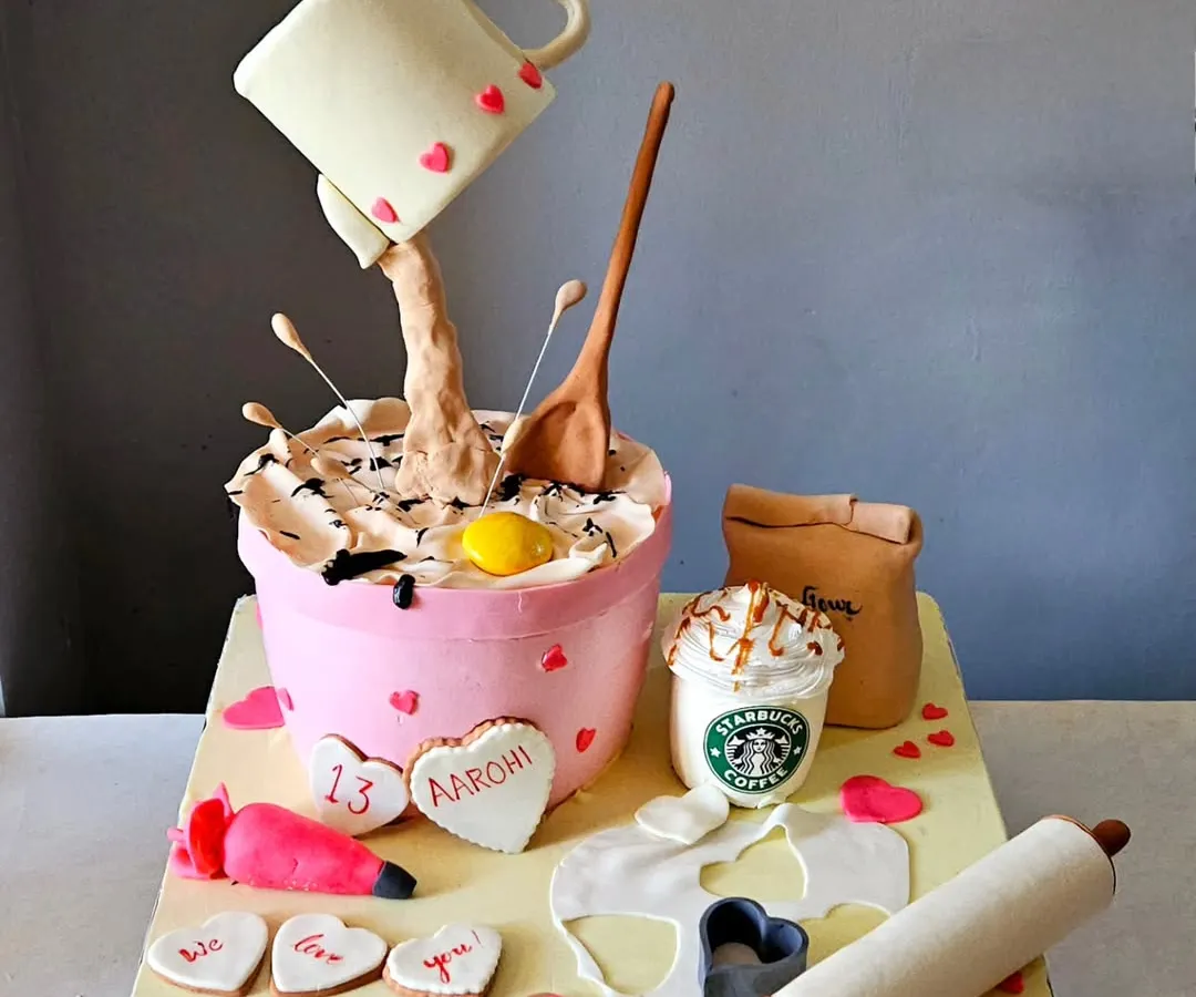 This cake was a joy to create for a young baker celebrating her 13th birthday. It features a gravity-defying design with a pouring mug, alongside edible baking tools like a rolling pin, piping bag, and even a miniature Starbucks cup. It’s a playful and complex piece that shows how we can turn any passion into a delicious work of art.