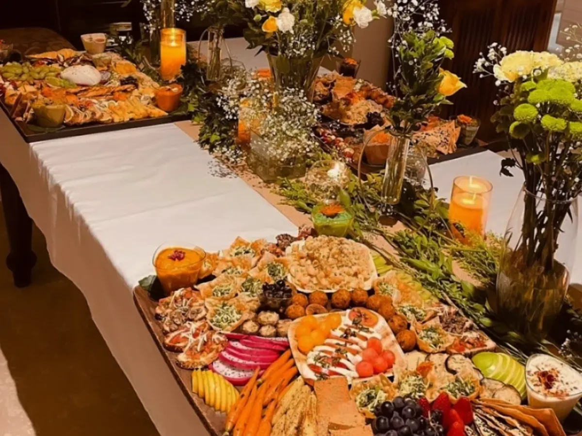 Flowers and candles sit between our grazing boards in this evening spread, with crackers, dips and little bites along the table.