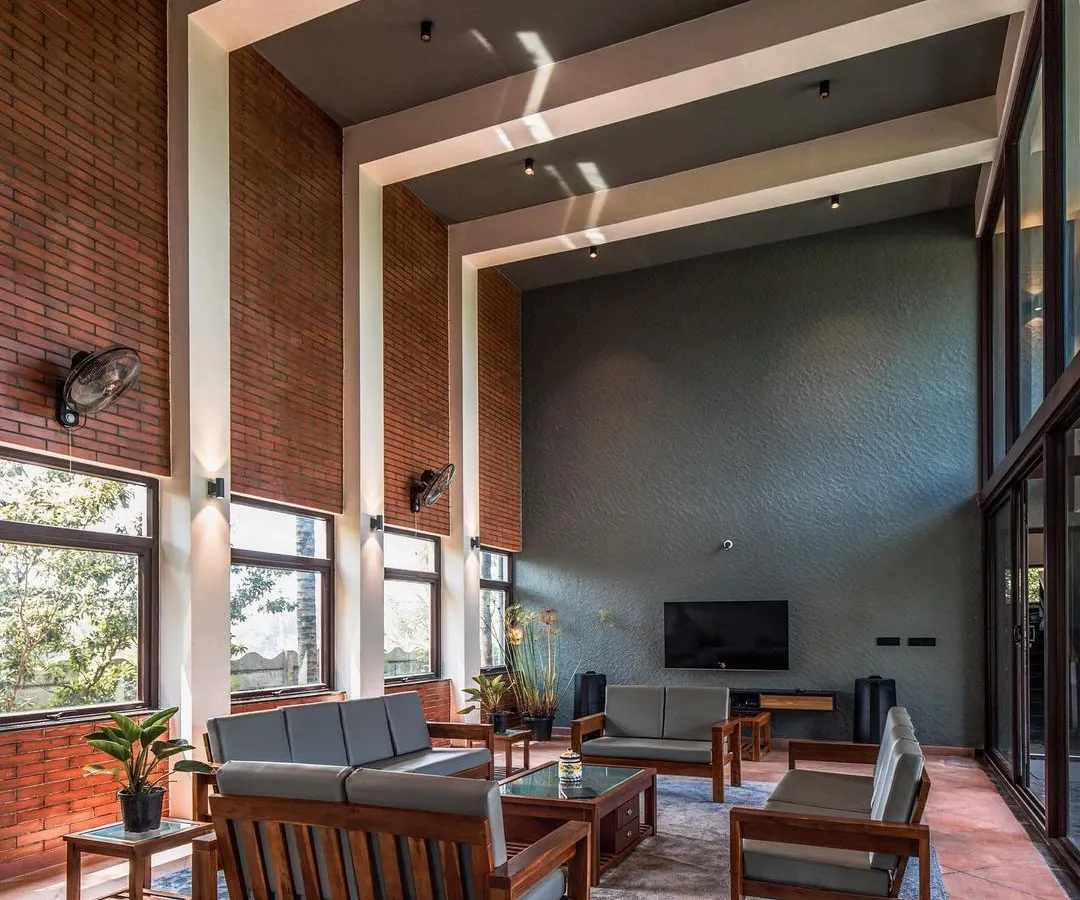 Inside The Grey Grotto, a double-height living area combines exposed brick walls and expansive glass panels. This space is designed to feel both grand and inviting, blurring the line between the interior and the lush exterior.