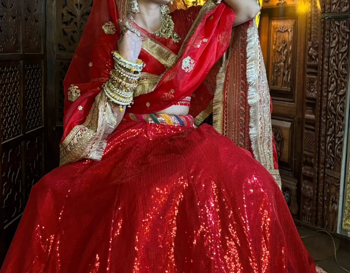 For the classic bride, nothing beats a stunning red lehenga. I've paired this sequined outfit with a complete gold-toned bridal jewellery set, including a choker, maang tikka, and stacked bangles, to create a timeless and royal wedding look.