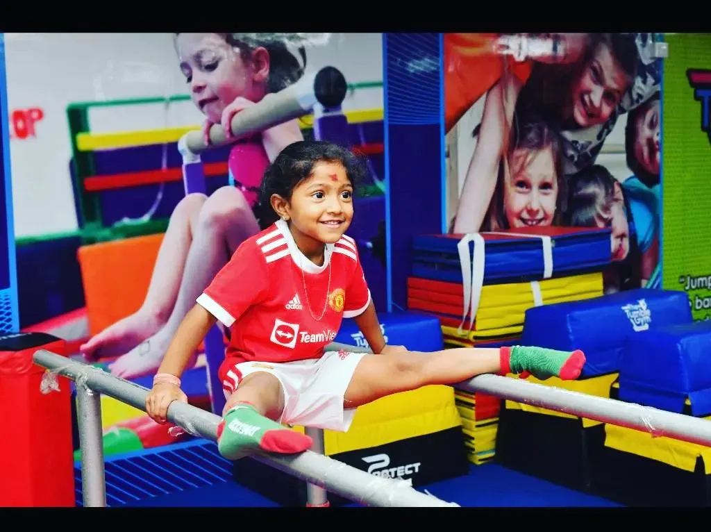 The smile of achievement. We celebrate every milestone, like mastering a split on the parallel bars, which builds not just flexibility but also immense self-confidence and body awareness.