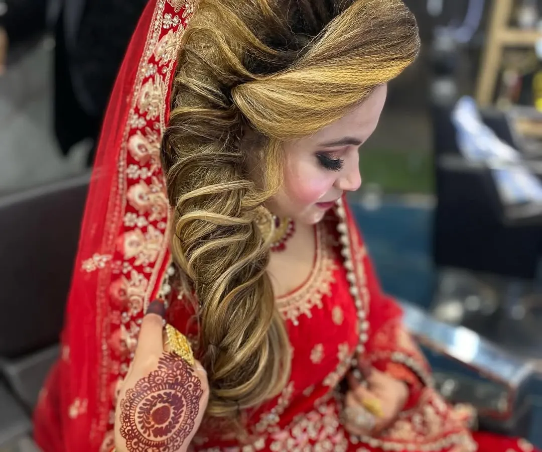 A stunning bridal look for a traditional wedding ceremony. I created this voluminous, side swept hairstyle with highlights to complement the bride's red lehenga and intricate makeup.