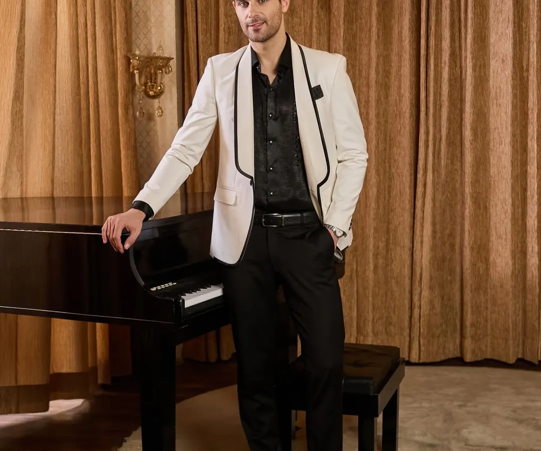 A timeless white tuxedo jacket with contrasting black shawl lapels, offering a sharp and sophisticated look for any cocktail party or reception. This bespoke piece is tailored for a clean silhouette that commands attention with quiet confidence.