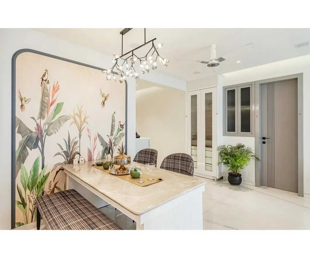 I believe a dining area should be an experience. Here, a stunning tropical-themed wallpaper creates a dramatic and artistic backdrop for a beautiful Italian marble dining table. Paired with a modern chandelier and a mix of bench and chair seating, this space is designed for memorable meals.