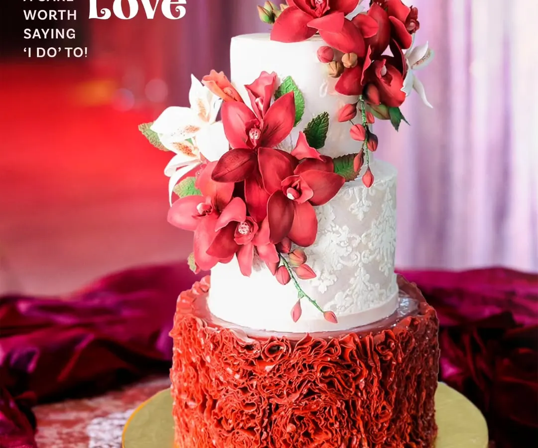 For the couple wanting to make a bold statement, this scarlet and ivory wedding cake combines passion with elegance. The design features a dramatic cascade of handcrafted red sugar orchids against delicate lace-patterned tiers and a vibrant ruffled base, creating a look of pure romance.
