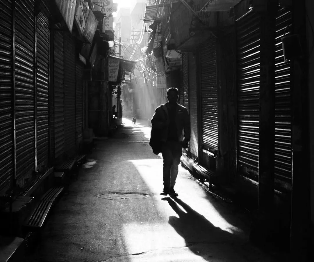 A man walks through a narrow, shuttered alley in Old Delhi, illuminated by a single shaft of morning light. This is the kind of poetic, high-contrast moment I am always searching for in my street photography.