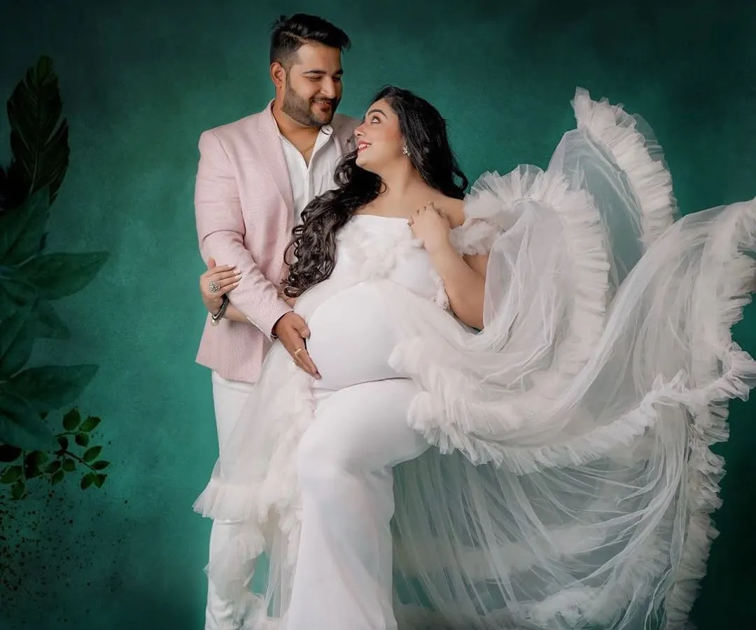 Creating a coordinated look for you and your partner is one of my favorite things to do. Here, my client wears a stunning white ruffled gown, perfectly complemented by a soft pink blazer for her partner, making their studio maternity session truly special.