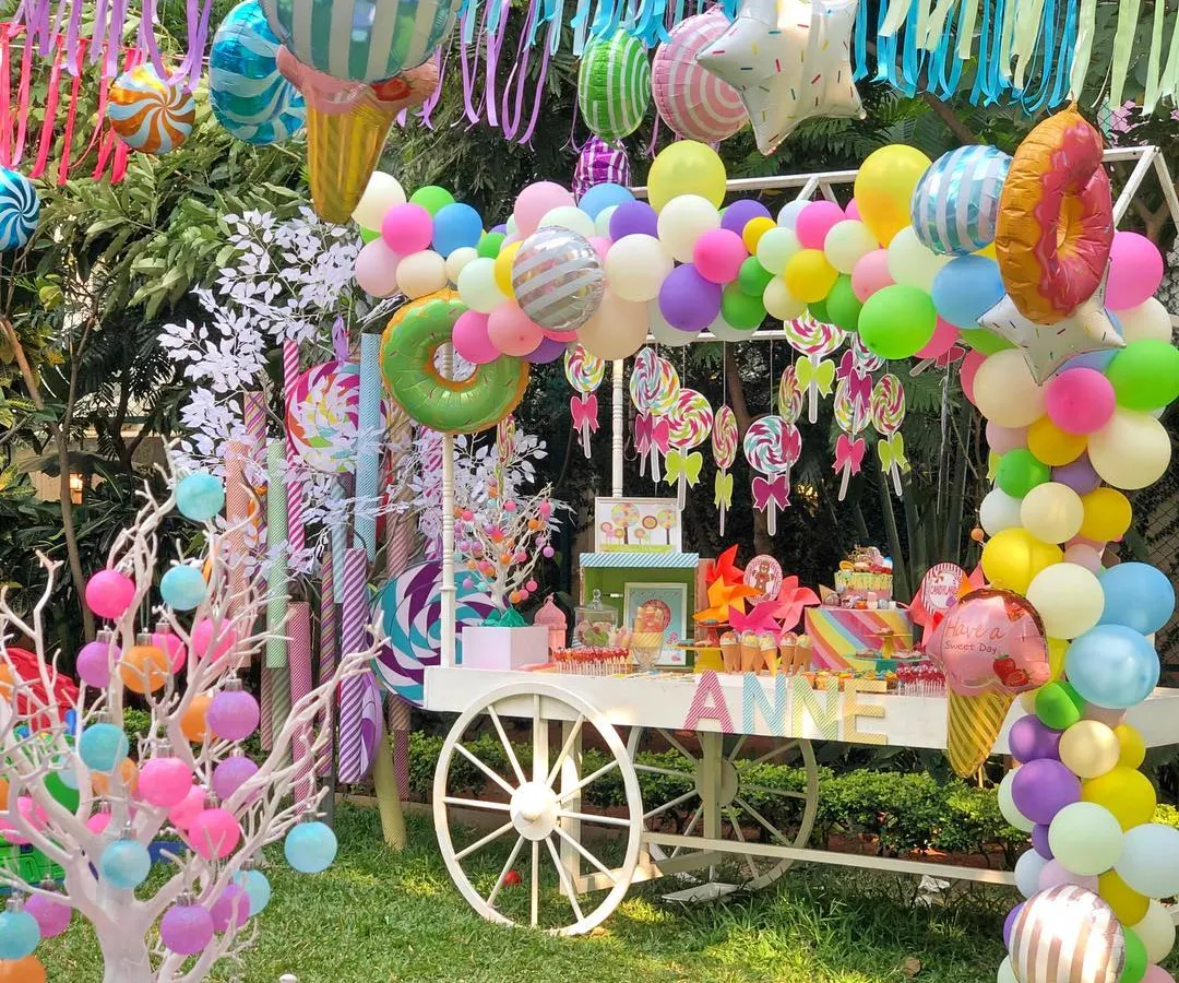 A vibrant Candyland themed birthday party, brought to life with a custom candy cart, a colorful balloon arch, and whimsical decorations. This outdoor setup was designed to be a child's dream, filled with sweets, treats, and playful details like oversized candy props.