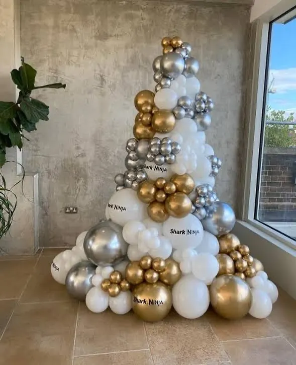 For a modern take on Christmas, I can build a custom balloon Christmas tree like this one. This installation uses a mix of white, chrome silver, and gold balloons in various sizes to create a stylish, festive structure that's perfect for corporate lobbies or contemporary homes.