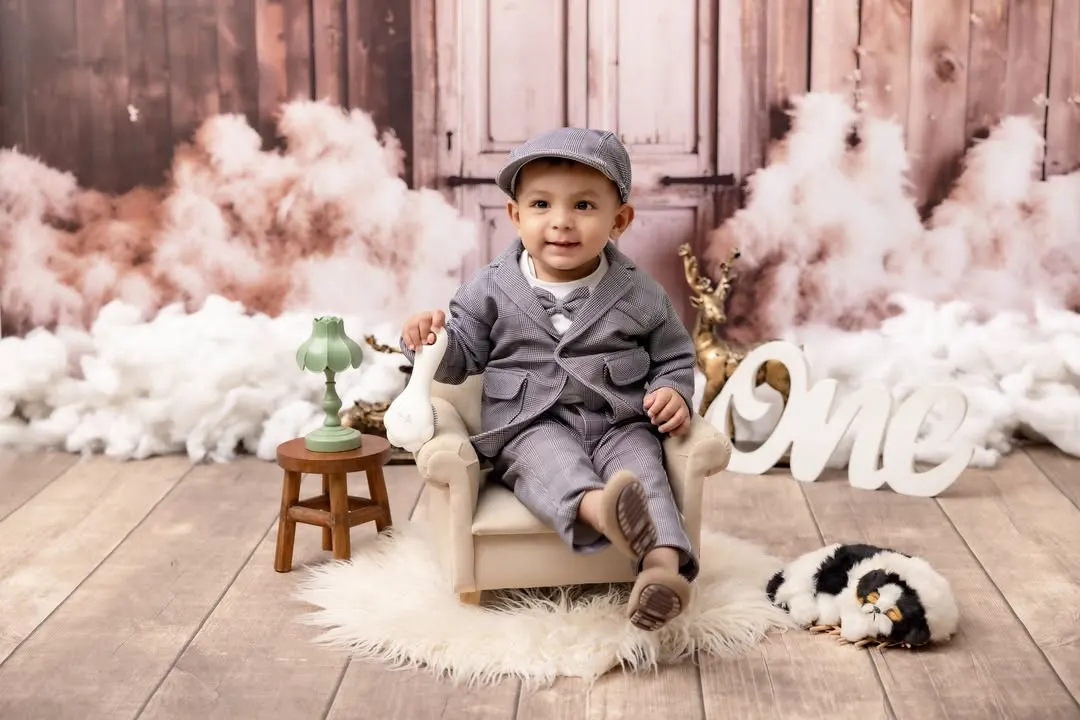 Celebrating one year of life with style and personality. This little gentleman is dressed in a dapper suit for his first birthday photoshoot, set against a classic, rustic backdrop that makes his big milestone feel even more special.